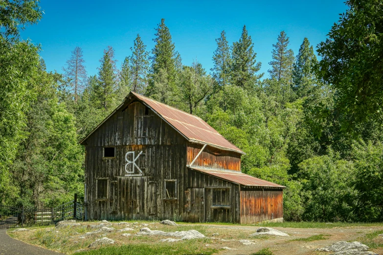 an old barn is near many tall trees