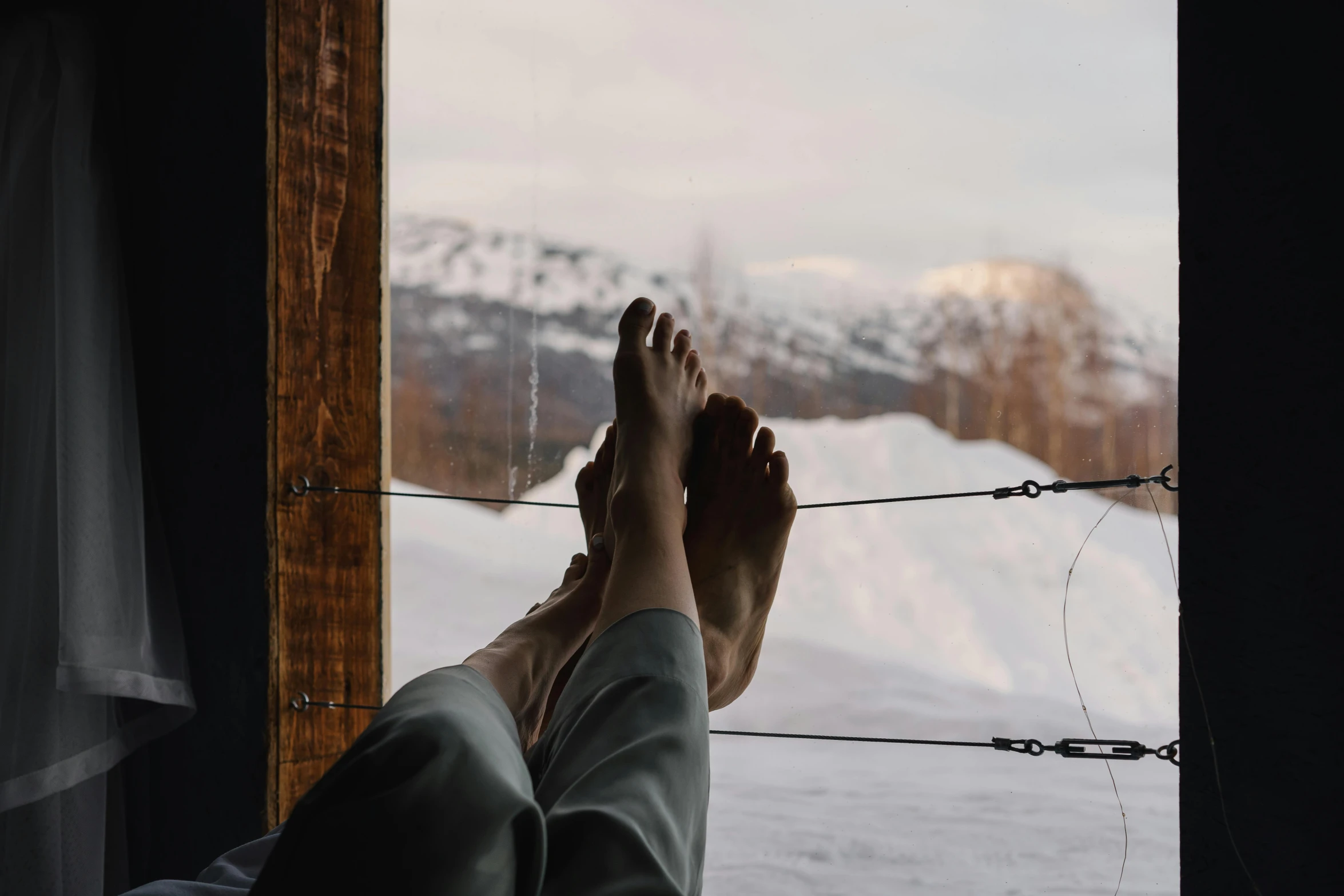 the feet of someone who is sitting by a snowy mountain