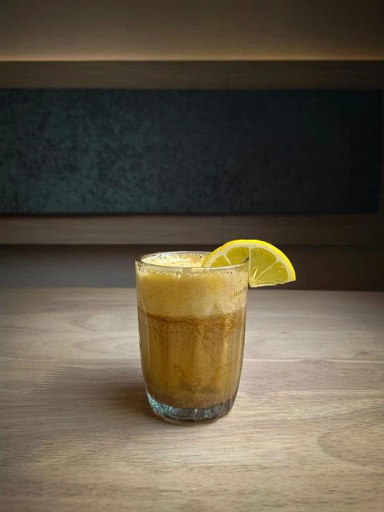 an orange slice sits atop the top of a tall glass