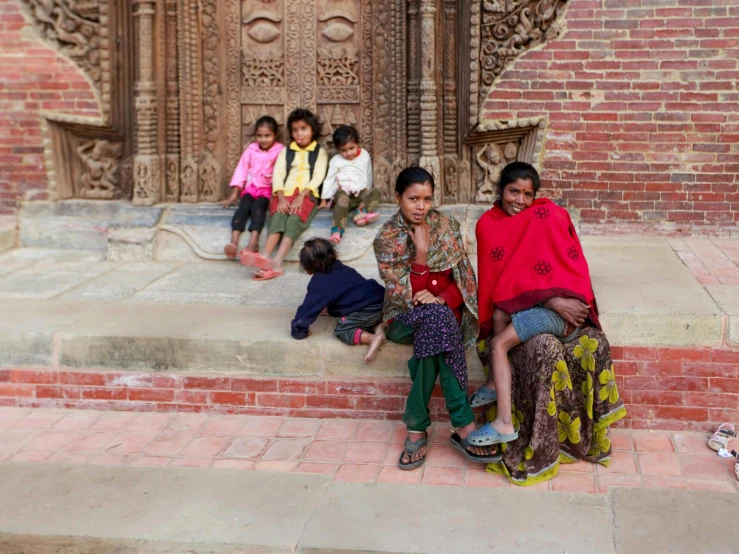three children and four adults are in front of an intricately designed building