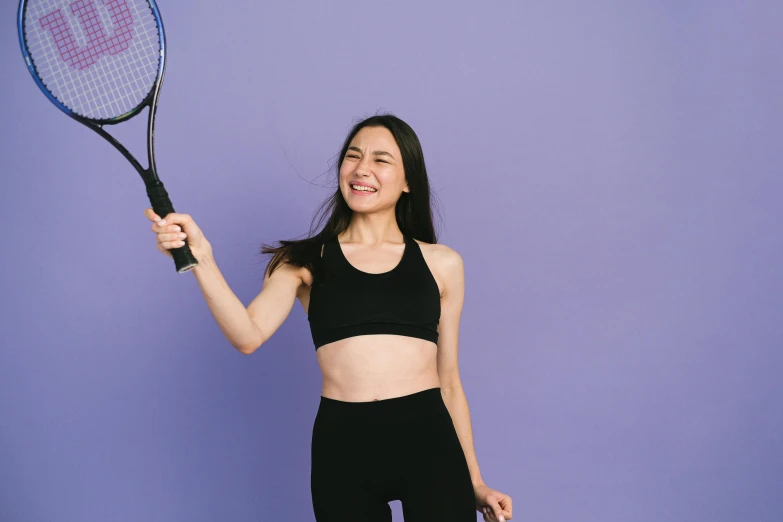 an adorable woman with a very excited look on her face holds a tennis racket