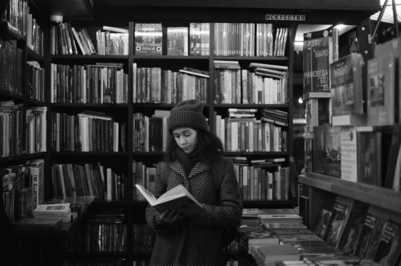 a woman reading in a liry with several book shelves full of books