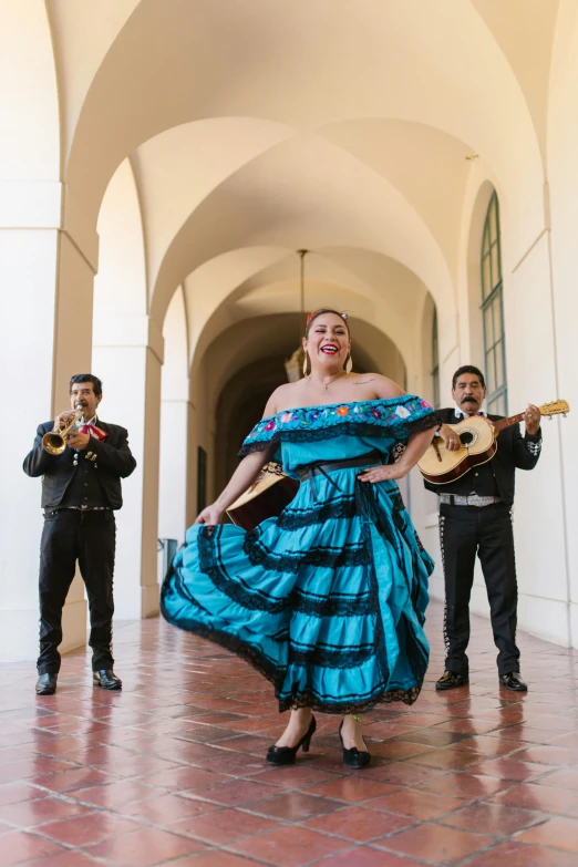 a woman playing a guitar while another man plays a guitar in a hallway