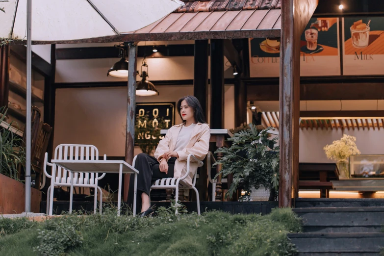 a woman in a cream jacket sitting in white plastic chairs