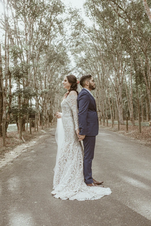 a couple poses in front of trees on the paved road