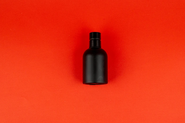 a small bottle sits next to an empty black plastic bottle