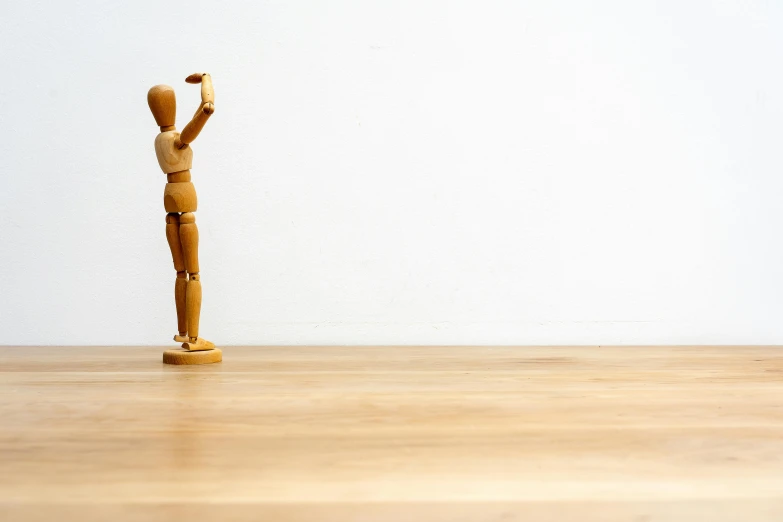 an old wooden stick figure standing upright on a wood floor