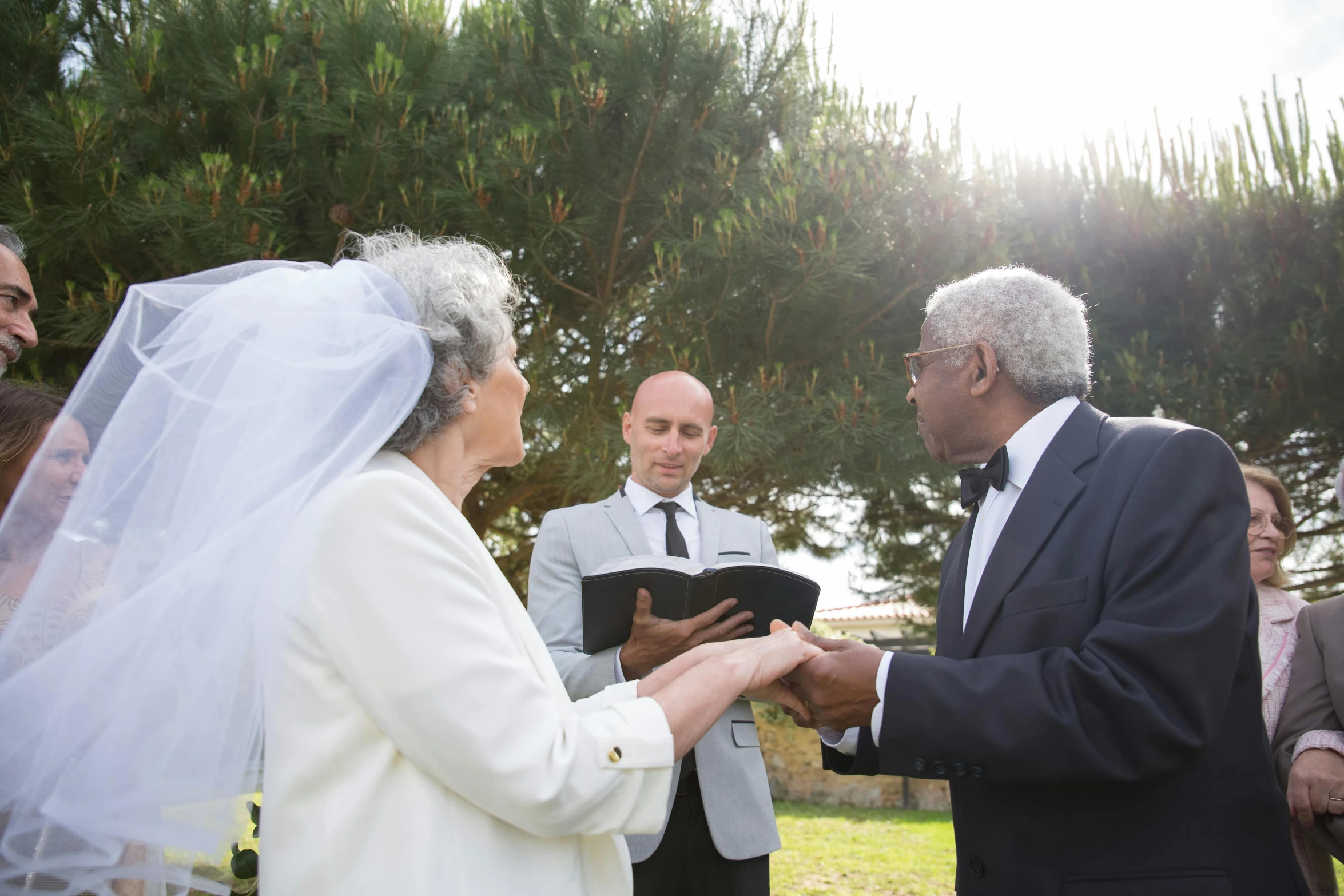 two adults are exchanging wedding rings at an outdoor ceremony