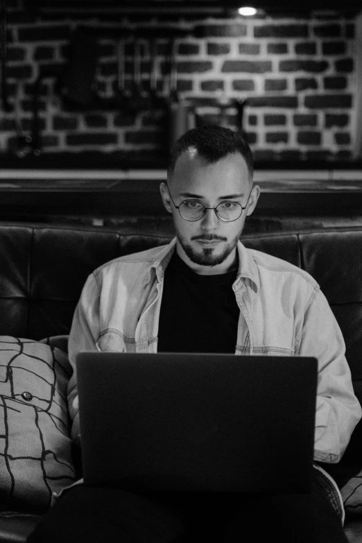 a man sitting on a couch working on his laptop