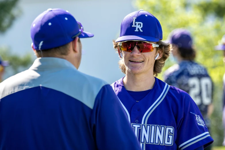 a baseball player smiles and talks to an assistant