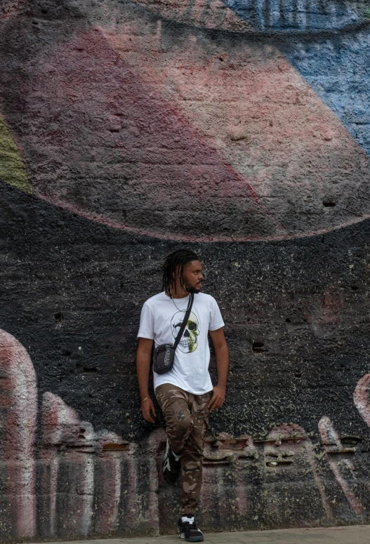 a man standing by graffiti as he talks on his phone