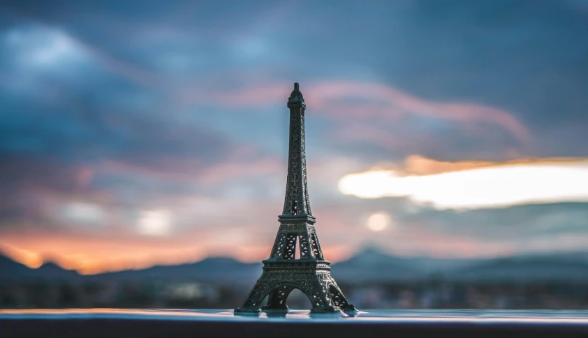 a miniature model of the eiffel tower against a sunset background