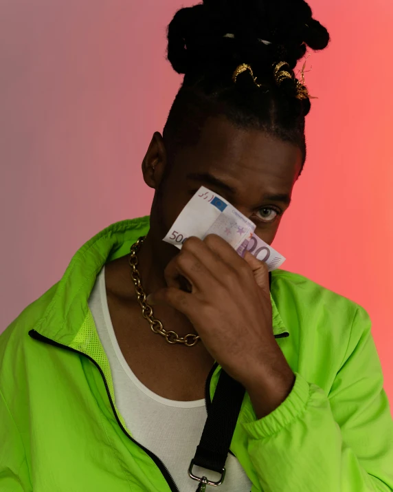 an african american woman in a green jacket looks at the camera while holding her face near her mouth