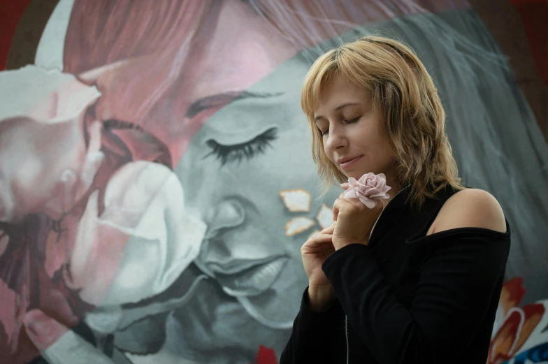 a woman wearing a black shirt and holding a pink flower in her hand