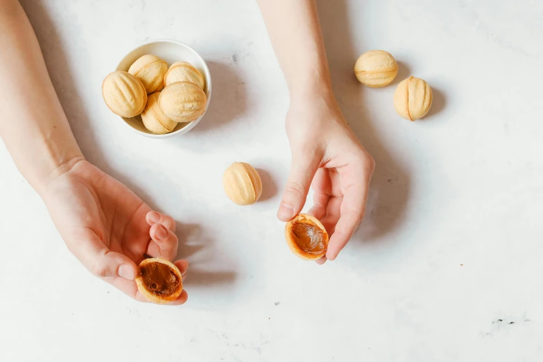two hands grabbing almonds from the shell on the table