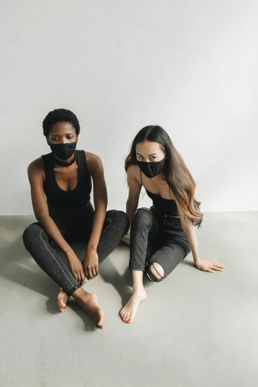 two girls pose while wearing a black mask