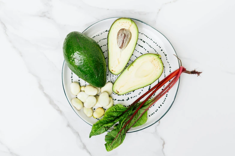 sliced avocados, red radishes, and greens on a plate