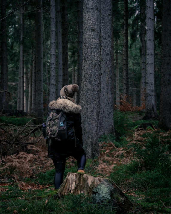 the person with a bag is standing by a tree