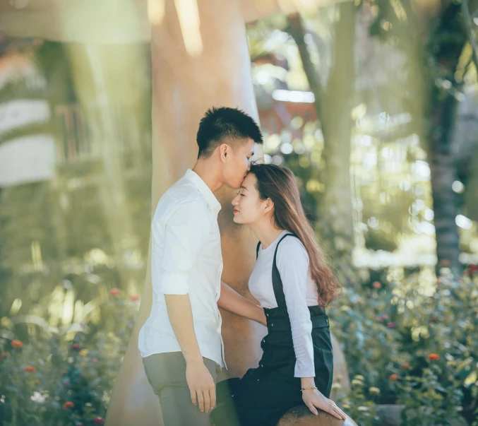 an asian couple sitting on the ground near a tree