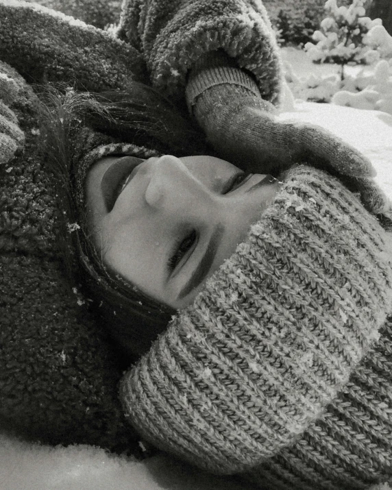 black and white image of a young person lying in the snow