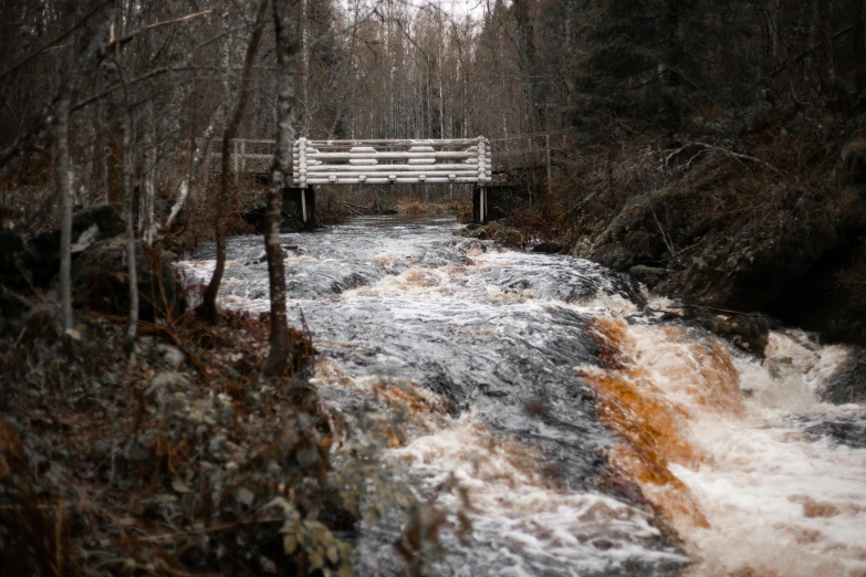 a white bridge is on a rushing creek