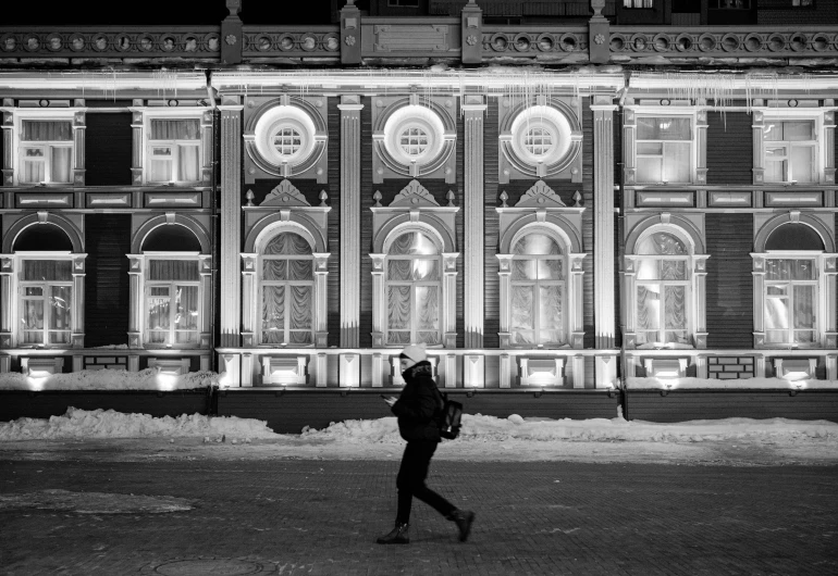 a man is walking in front of a building at night