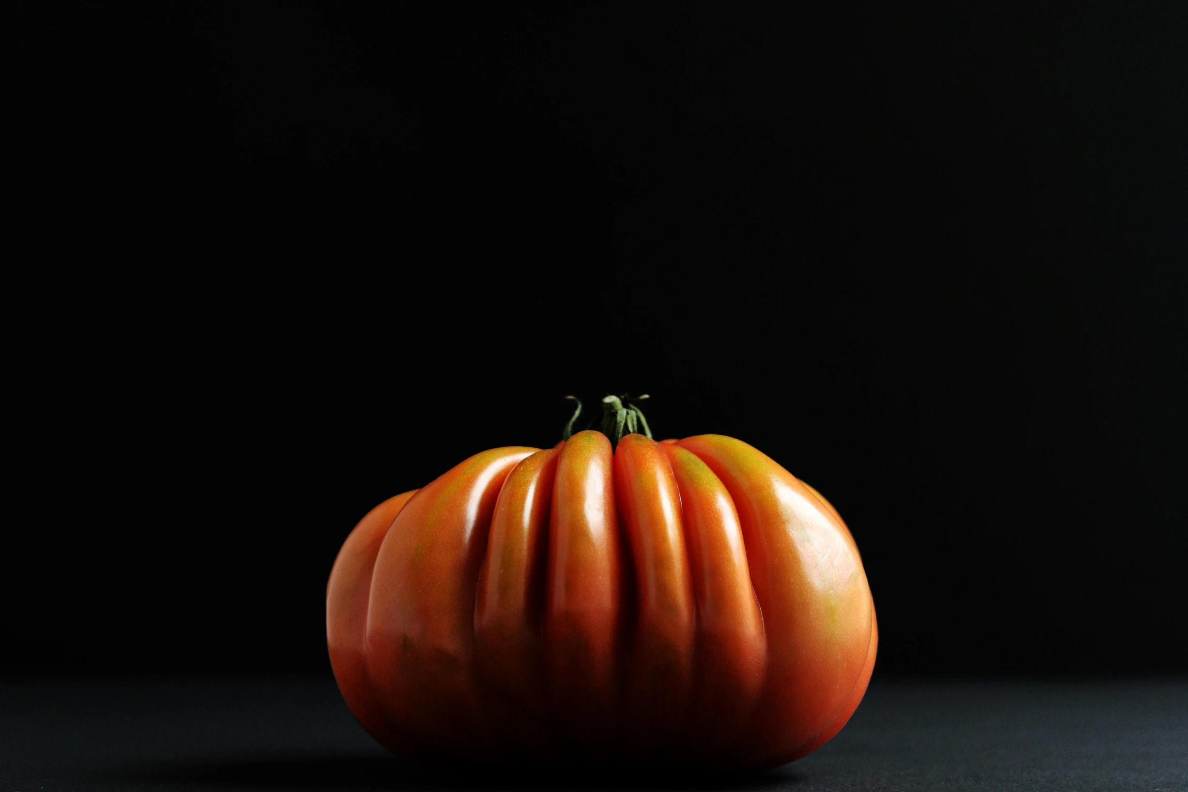 an orange pumpkin that is on a dark surface