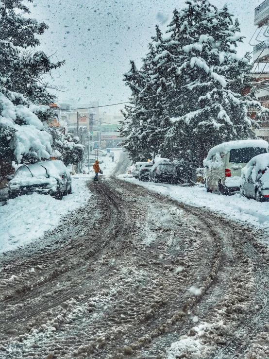 vehicles parked on a snowy road in the middle of a town