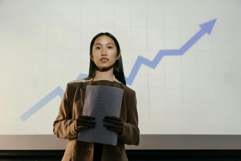 a woman is standing next to a screen holding a piece of paper