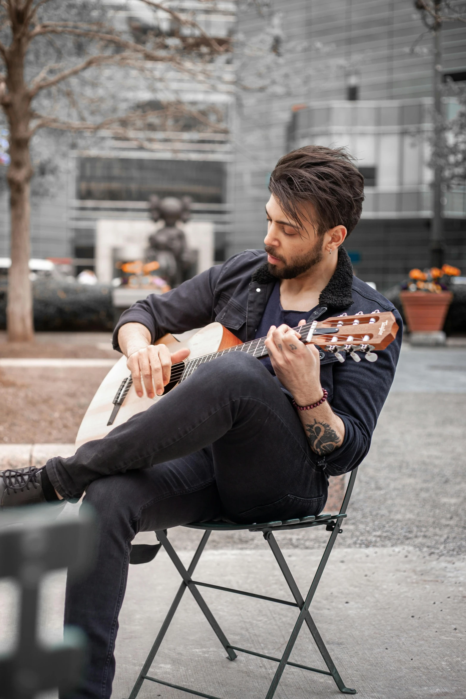 a man sitting on top of a folding chair holding a guitar