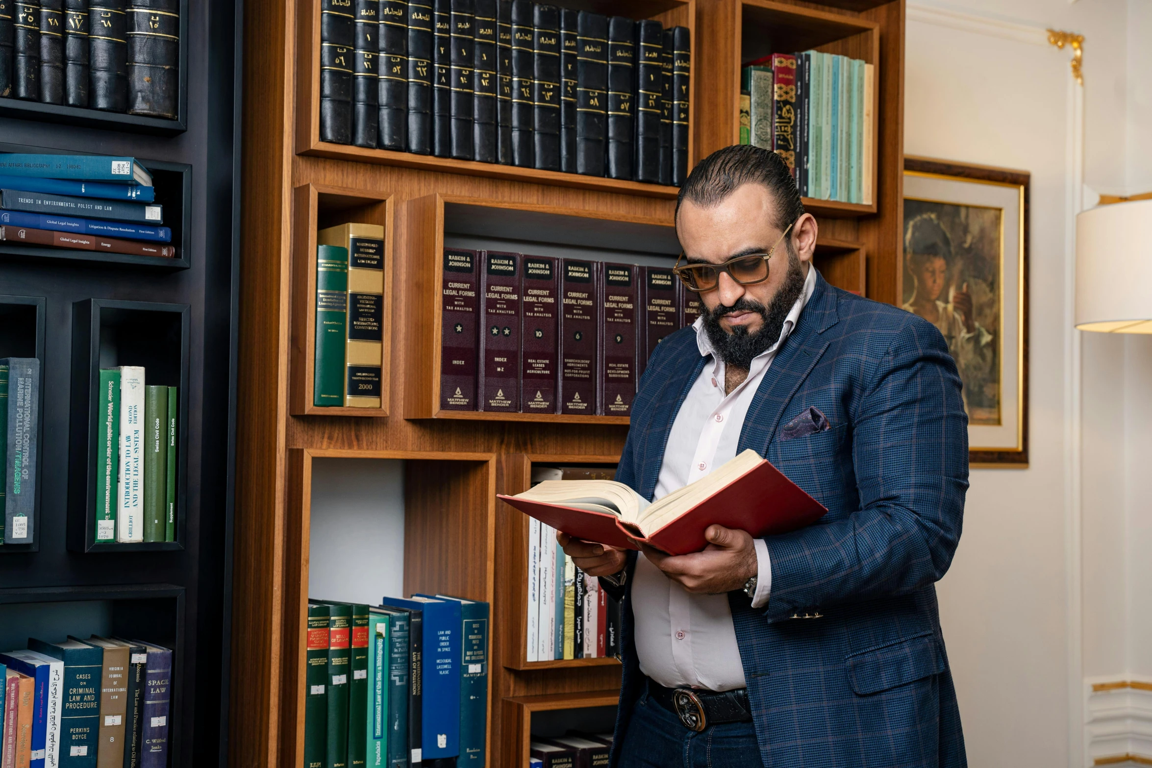 man in suite jacket reading book near bookshelves