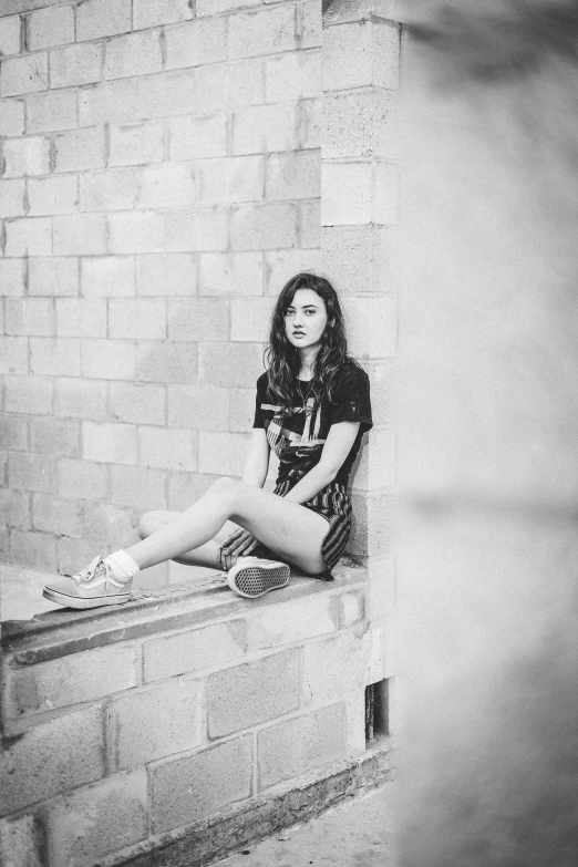 a woman is sitting on the ledge looking at the camera