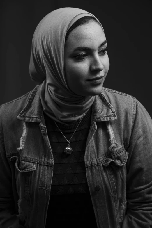 an older women with a hood standing against a wall