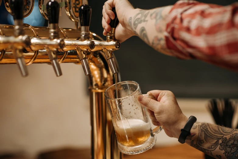 a man pours beer from a glass into a mug