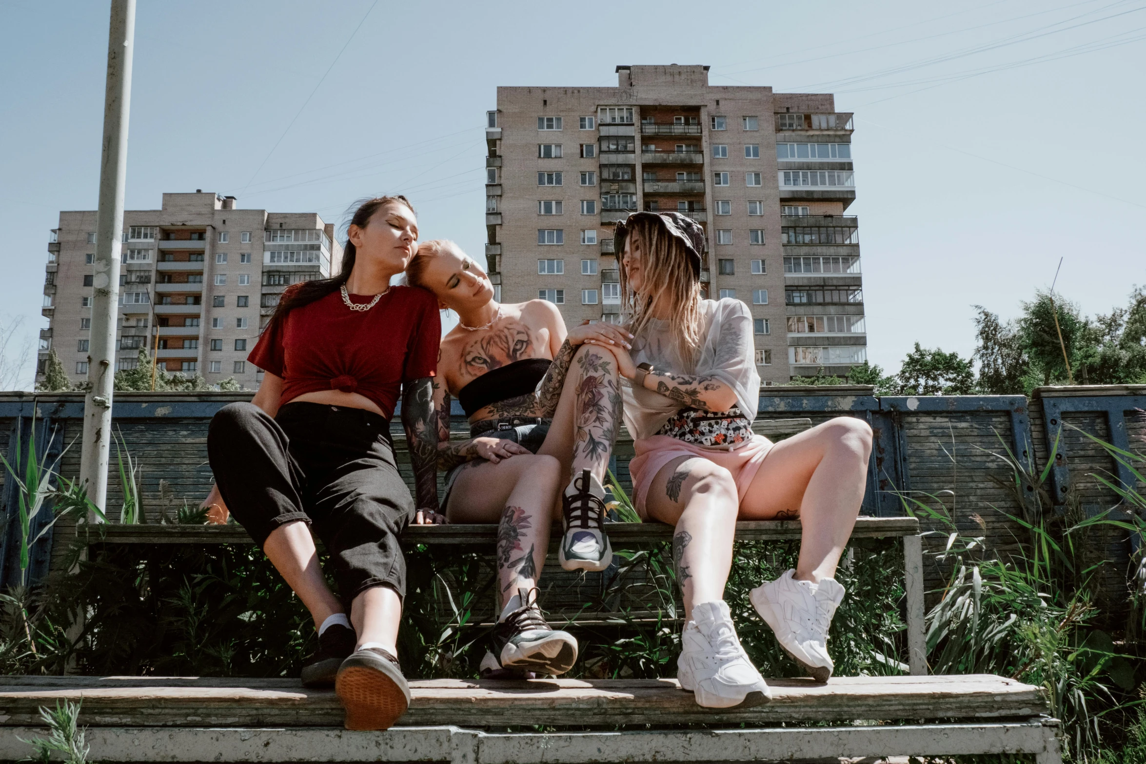 three women sitting on a bench in the middle of city