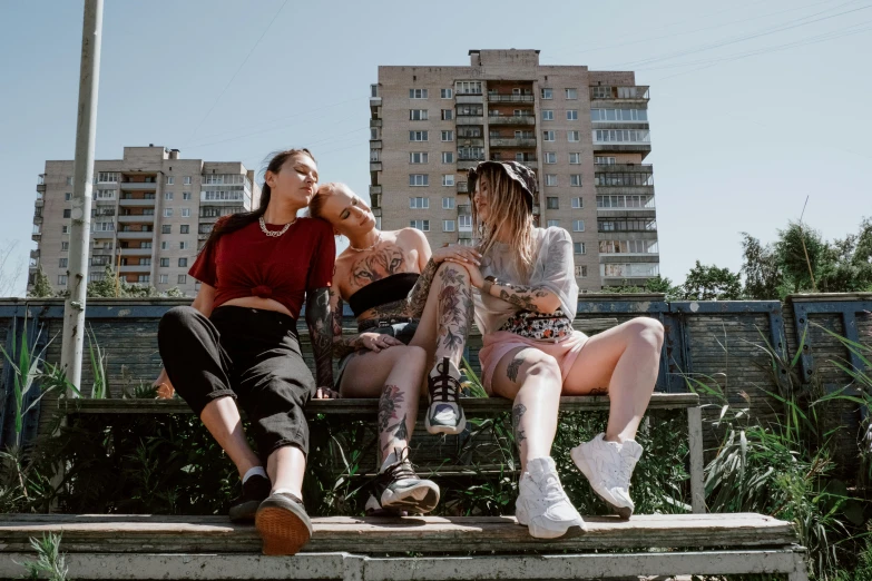 three women sitting on a bench in the middle of city