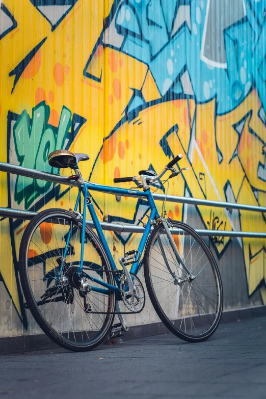 two bicycles leaning against a yellow graffiti wall