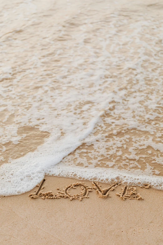 the word love drawn on sand at the shore