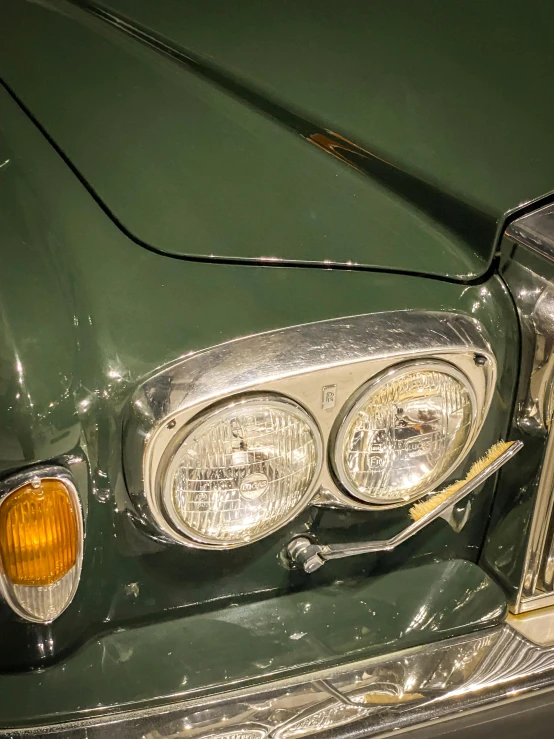 a close up view of the front lights on an older green car