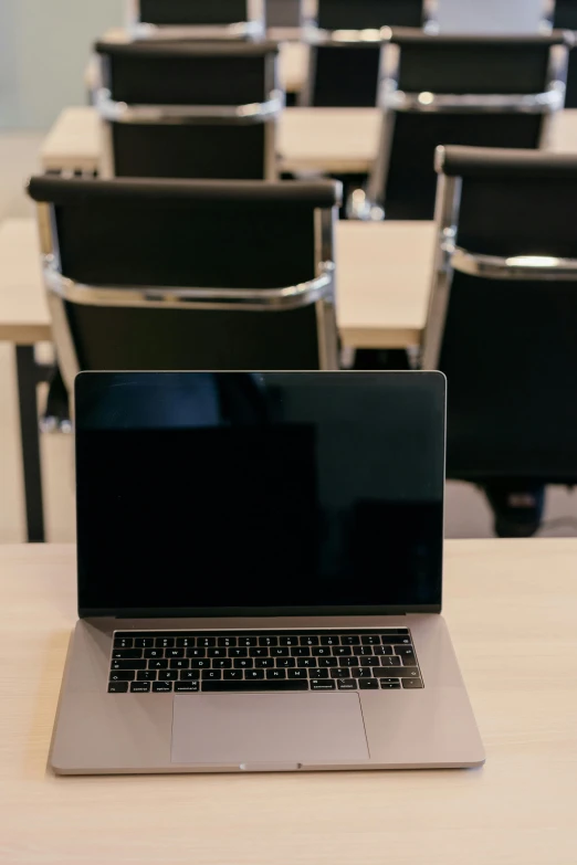 a laptop sitting on a table in a classroom