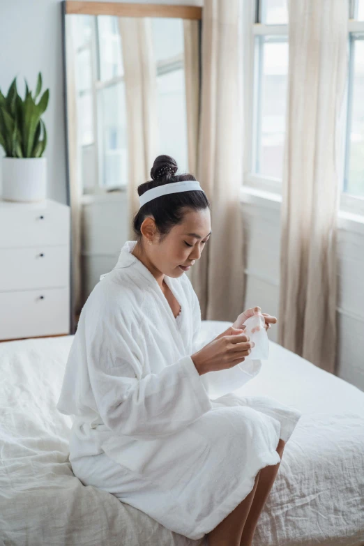 a woman sitting on a bed in a bathrobe