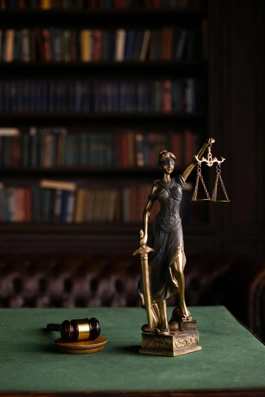 a statue is on a book shelf next to a scale of justice