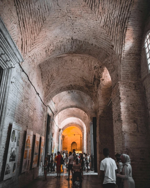 people standing in a stone tunnel looking at paintings