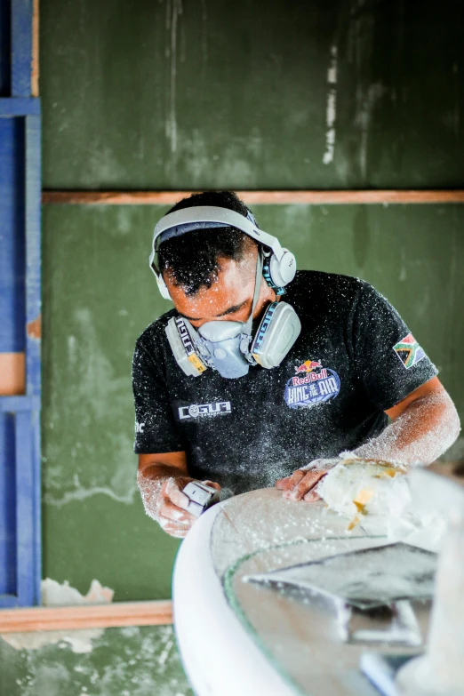 a man wearing earphones and a protective mask, washing a car in a sink