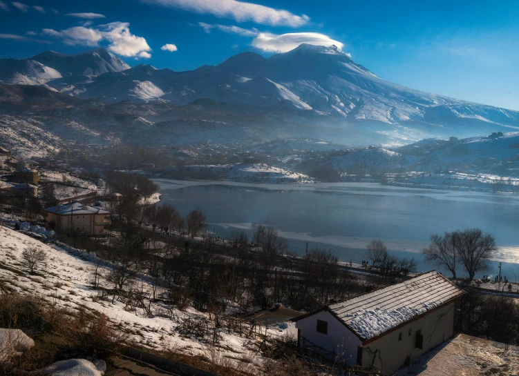 an aerial po of a snowy mountain range with a small house in front