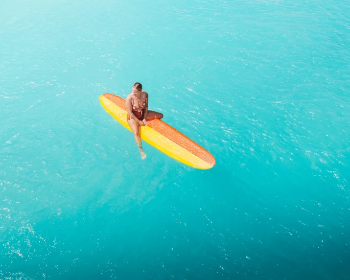 man on a surfboard paddling across a large body of water