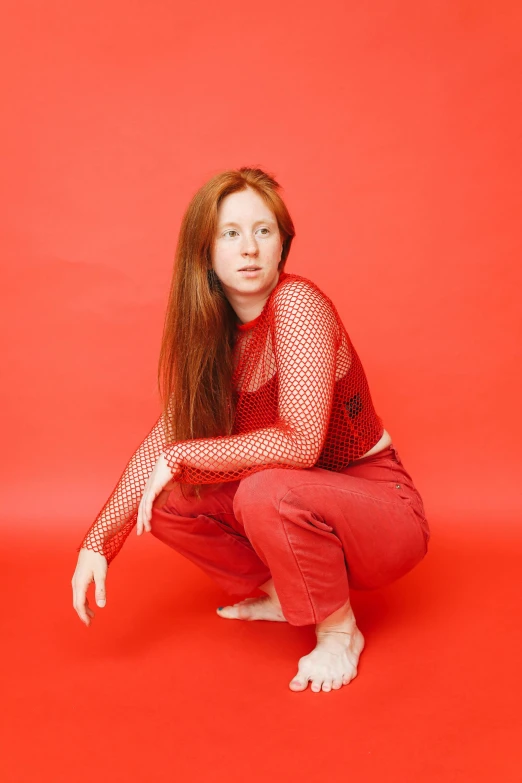 a woman posing for a pograph against a red background