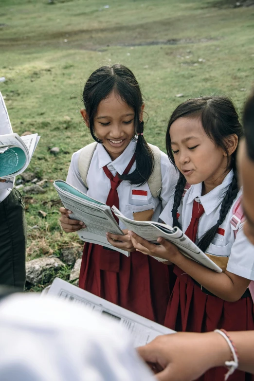 three s in school uniform are reading books