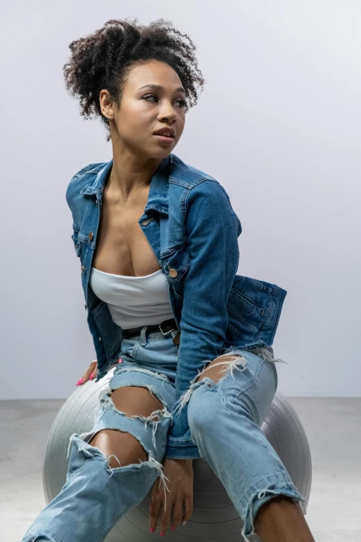a woman in jean jacket and ripped jeans posing