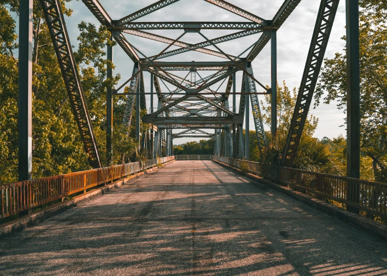 the view from the road of a steel truss bridge that crosses over the river